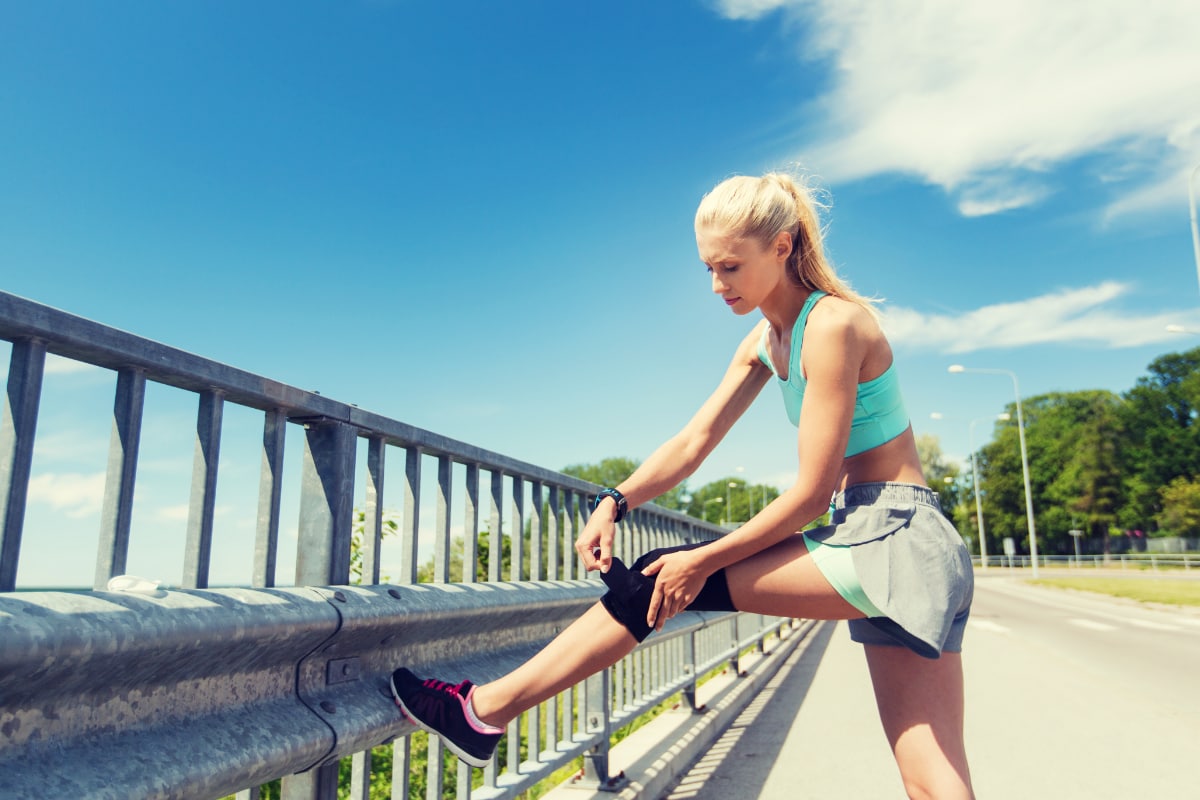 woman adjusting knee brace during run session